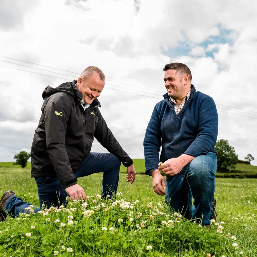 Germinal expert David Little crouching beside a farmer and clover