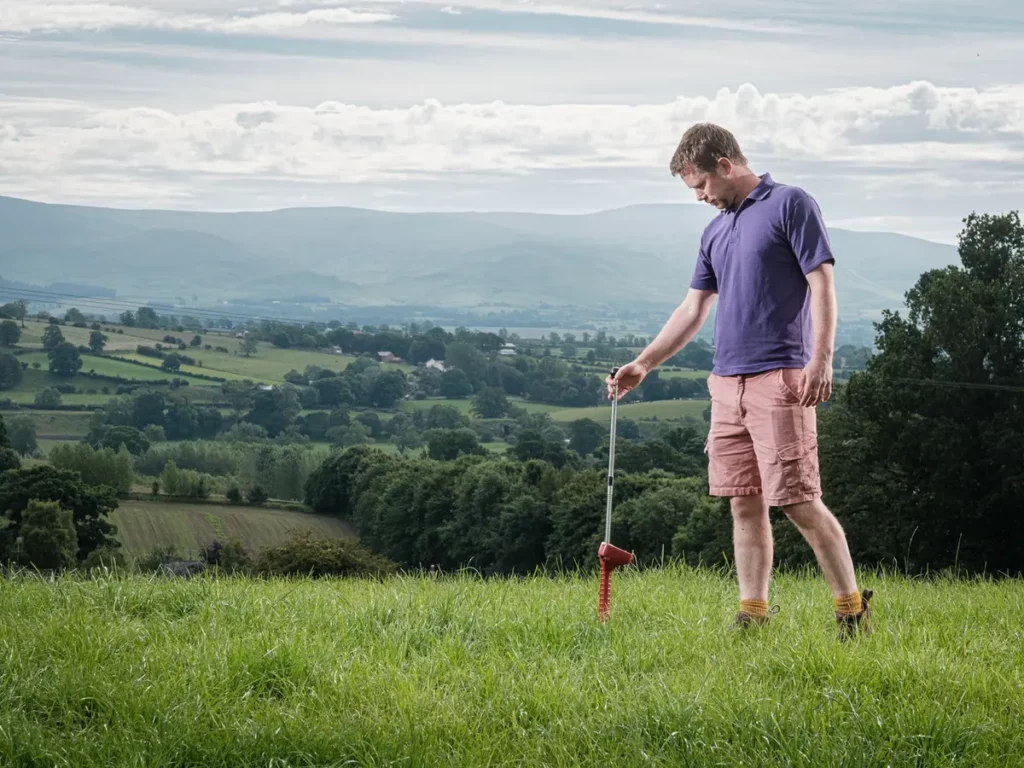 Cumbrian dairy farmer James Tweedie walking in a field with hills in the distance.